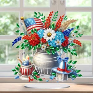 Könnte beinhalten: Eine patriotische Blumengesteck in einer silbernen Vase, mit roten, weißen und blauen Blumen, einer amerikanischen Flagge und dekorativen Elementen. Enthält eine Teetasse mit Kerzen und einen Hut, alles im festlichen Stil.