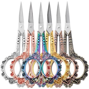 May include: Set of six decorative scissors with ornate handles. The scissors are in various colors, including silver, rose gold, gold, purple, and black.