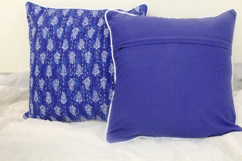 May include: Two decorative throw pillows with white piping. One pillow has a blue and white floral pattern, and the other is solid blue.