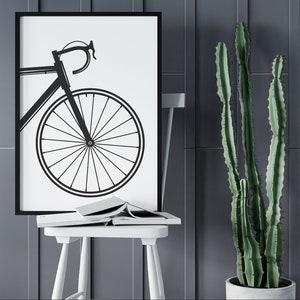 Pu&ograve; includere: Silhouette in bianco e nero di una bicicletta con un telaio sottile e ruote grandi su sfondo bianco. L'immagine &egrave; incorniciata in nero e appesa a una parete grigia.