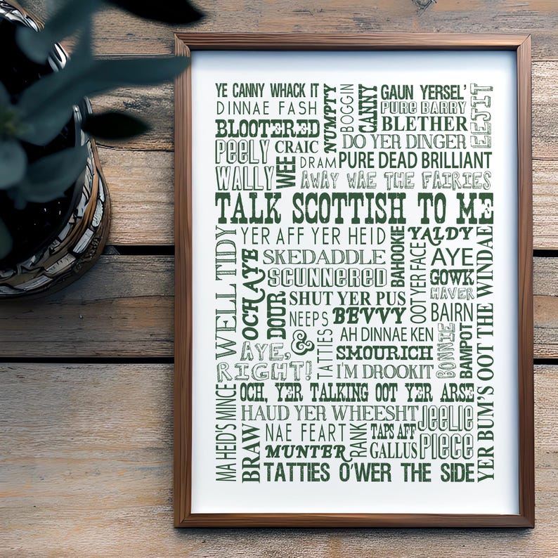 May include: A framed wall art print featuring a collection of Scottish slang words and phrases in various green and gray fonts. The text includes phrases like Talk Scottish To Me, Ye Canny Whack It, and Pure Dead Brilliant, arranged in a dense, vertical typographic layout on a white background.