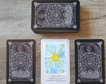 Puede incluir: Una carta de tarot con un sol amarillo sobre un fondo azul. La carta está etiquetada como "SOLEIL / SUN" y tiene el texto "renacimiento, energía, éxito, logro, energía, éxito" en la parte inferior. La carta está rodeada por otras tres cartas con un diseño en blanco y negro.