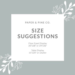 May include: A white rectangle with gray text on a light gray background. The text reads "PAPER & PINE CO. SIZE SUGGESTIONS Floor Easel Display 20"x28" or 24"x36" Table Display 15"x20" or smaller". The rectangle is surrounded by white floral designs.