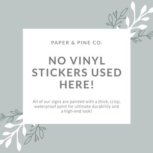 Peut inclure: Un carr&eacute; blanc aux coins arrondis sur un fond bleu clair avec des motifs floraux blancs et gris. Le carr&eacute; contient le texte "PAPER & PINE CO." en gris, suivi de "NO VINYL STICKERS USED HERE!" en gris plus grand. En dessous du texte, une description en gris indique "All of our signs are painted with a thick, crisp, waterproof paint for ultimate durability and a high-end look!"