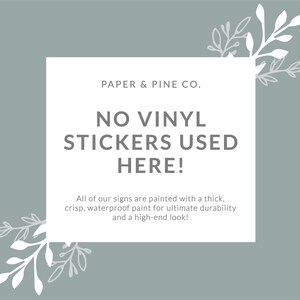 Peut inclure: Une pancarte blanche avec un fond gris et des branches feuillues vertes de chaque c&ocirc;t&eacute;. La pancarte indique "PAPER & PINE CO. NO VINYL STICKERS USED HERE! All of our signs are painted with a thick, crisp, waterproof paint for ultimate durability and a high-end look!"
