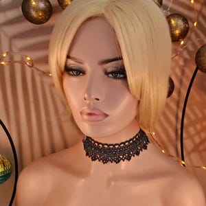 Pu&ograve; includere: Primo piano di una donna che indossa un girocollo in pizzo nero. Il girocollo ha un design delicato ed &egrave; realizzato con materiali pregiati.