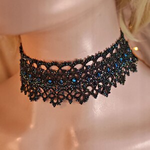 Pu&ograve; includere: Un girocollo in pizzo nero con perline blu iridescenti. Il girocollo &egrave; delicato e intricato, con un bordo a festoni.