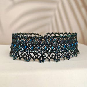 Pu&ograve; includere: Collana choker nera con perline blu iridescenti. La collana &egrave; realizzata in pizzo delicato e presenta un design delicato e intricato.