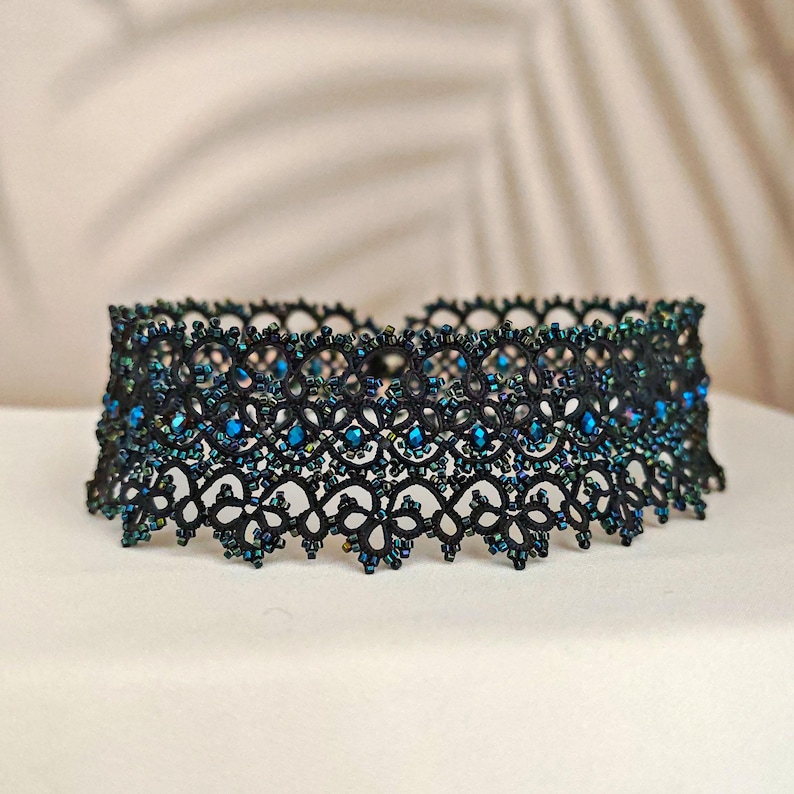 Pu&ograve; includere: Collana choker nera con perline blu iridescenti. La collana &egrave; realizzata in pizzo delicato e presenta un design delicato e intricato.