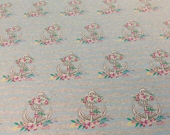 May include: A light blue fabric with a repeating pattern of white anchors with pink flowers. The anchors are surrounded by green leaves and the background has a subtle striped pattern.