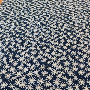 May include: A navy blue fabric with a white floral pattern. The fabric is covered in small white flowers.