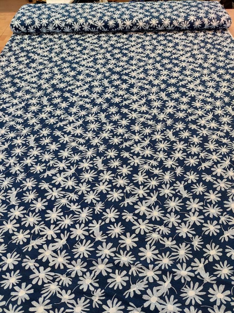May include: A navy blue fabric with a white floral pattern. The fabric is covered in small white flowers.