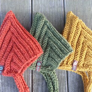 May include: Three knitted hats in orange, green, and yellow with a brown tag that says "Bl&uuml;m" on each hat.