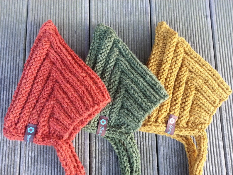 May include: Three knitted hats in orange, green, and yellow with a brown tag that says "Bl&uuml;m" on each hat.