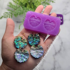May include: A purple silicone mould with two leaf shapes. Two pairs of iridescent leaf earrings are shown next to the mould.