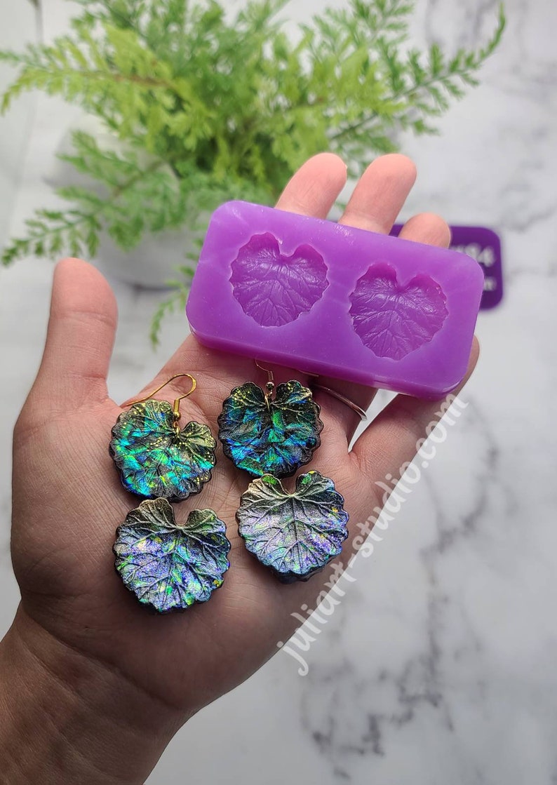 May include: A purple silicone mould with two leaf shapes. Two pairs of iridescent leaf earrings are shown next to the mould.