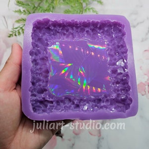 May include: Purple silicone mould with a textured, crystal-like design. The mould has a rectangular shape with a square opening in the centre. The opening is filled with a clear, iridescent film.