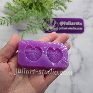 May include: Purple silicone mould with two leaf-shaped cavities. The mould is designed for creating resin or polymer clay crafts.