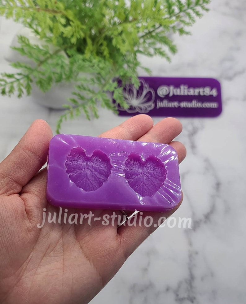 May include: Purple silicone mould with two leaf-shaped cavities. The mould is designed for creating resin or polymer clay crafts.