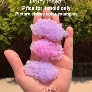 May include: Three different colored resin druzy inserts, each measuring 2.25 to 2.5 inches. The inserts are in shades of purple and pink, and are displayed on a hand. The text "Price for 1 mold only" and "Picture shows color examples" is visible above the inserts.