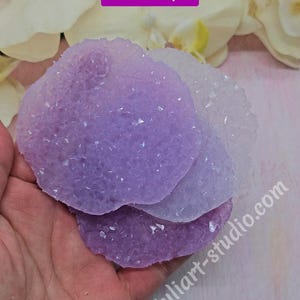 May include: Three layered, textured, resin art pieces in shades of purple and white. The pieces are held in a hand, with the text "Color Examples" in a purple box. The website address "juliart-studio.com" is visible.