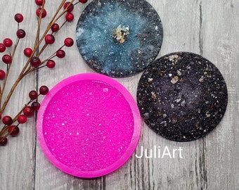 Könnte beinhalten: Das Bild zeigt drei runde Untersetzer mit einem Durchmesser von etwa 10 cm, zusammen mit einer rosa Silikonform. Die Untersetzer haben gesprenkelte Designs in Blau und Schwarz. Der Text lautet "4 inch Round Druzy Coaster Silicone Mold."