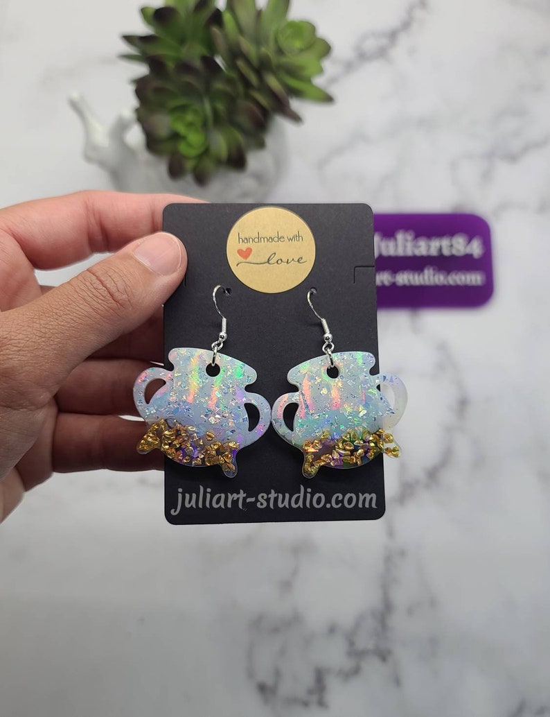 K&ouml;nnte beinhalten: Ein Paar regenbogenfarbene wei&szlig;e Kessel-Ohrringe mit goldenen Glitzerakzenten. Die Ohrringe sind handgefertigt mit Liebe und haben einen silbernen Haken.