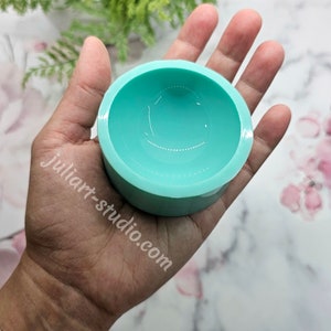 May include: A teal silicone mould for making resin crafts. The mould is shaped like a shallow bowl with a rounded bottom.