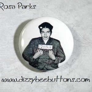 May include: Black and white photo of Rosa Parks, a civil rights activist, holding a sign that reads "705.3". The photo is on a white button.