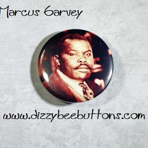 May include: A button featuring a black and white photo of Marcus Garvey, a prominent figure in the Pan-African movement. The button is round and has a white background. The text "Marcus Garvey" is printed above the photo, and "www.dizzybeebuttons.com" is printed below the photo.