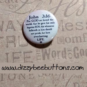May include: White button with black text that reads "John 3:16 For GOD so loved the world, that he gave his only begotten SON, that whosoever believeth in him should not perish, but have everlasting LIFE."