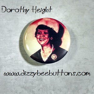 May include: A vintage button featuring a black and white photo of Dorothy Height, a civil rights activist. The button is round and has a white background with a red border. The text "Dorothy Height" is printed in black at the top of the button.
