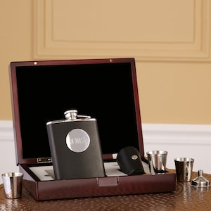 May include: A black and silver flask with a personalized monogram in a wooden box with two shot glasses and a funnel.