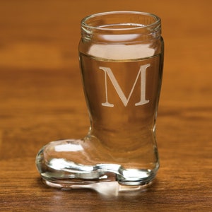 May include: A clear glass boot shot glass with the letter "M" etched on the side.