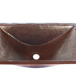 May include: A rectangular copper sink with a hammered finish. The sink has a single drain hole in the center.