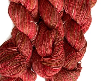 Hand-dyed cotton thick and thin yarn, 525 yard skeins, in shades of red, pink, beige, and brown