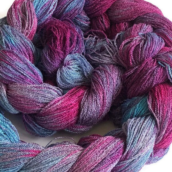 Hand-dyed, pre-wound weaving warp, 8/2 cotton and rayon, 200 ends, 4 3/4 yards long, in shades of blues, pinks, and red-purple
