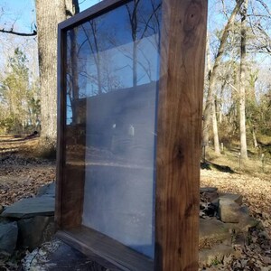 Pode incluir: Uma vitrine de madeira com frente de vidro. A vitrine &eacute; de madeira escura e tem um design simples.