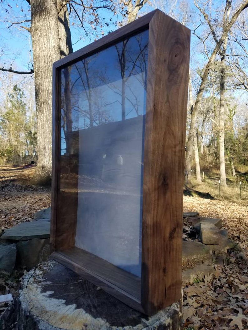 Pode incluir: Uma vitrine de madeira com frente de vidro. A vitrine &eacute; de madeira escura e tem um design simples.