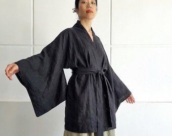 May include: A black wrap-style jacket with wide sleeves and a matching tie belt, paired with a long, flowing olive green skirt. The garment features the text bay bay baybaylinen.com printed in the lower right corner of the image.