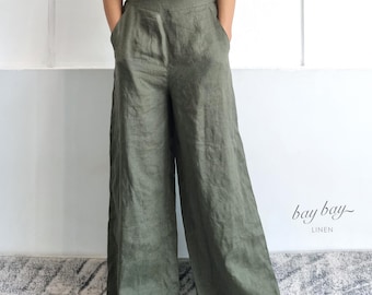 May include: A woman wearing a taupe-colored crop top and olive green linen wide-leg pants. The pants have pockets and a relaxed fit. The image is set against a white background. The brand name "bay bay~ LINEN" is visible.