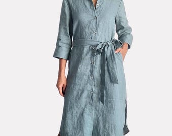 Peut inclure: Une robe chemise mi-longue vert sauge dotée d'un col classique, d'une fermeture boutonnée sur toute la longueur et de manches trois-quarts. Le vêtement comprend une ceinture à nouer assortie à la taille et des fentes latérales à l'ourlet.