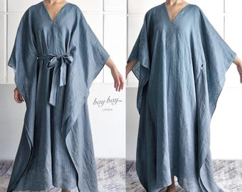 May include: A floor-length blue linen kaftan dress featuring a V-neckline, wide kimono-style sleeves, and a matching tie belt at the waist. The garment is shown with and without the belt, and includes the text bay bay LINEN printed on the fabric.