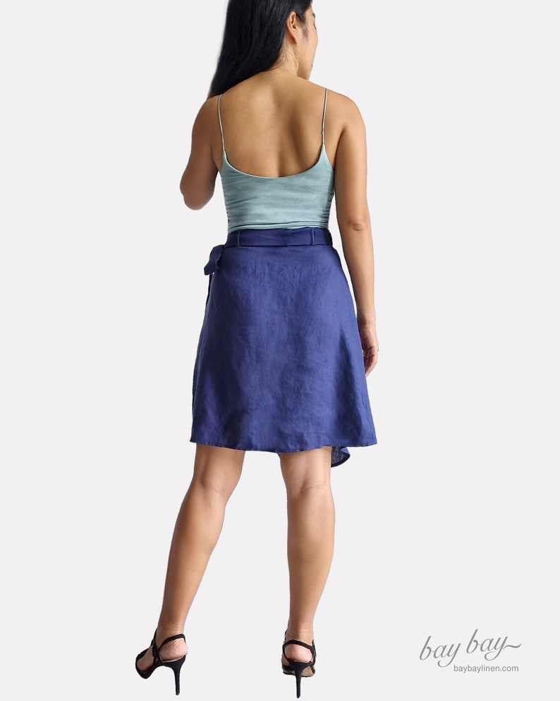 May include: A navy blue linen wrap skirt with a tie belt. The skirt is knee-length and has a flowy, A-line silhouette.