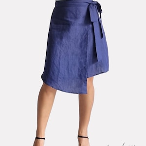 May include: A navy blue linen wrap skirt with a self-tie sash. The skirt is asymmetrical and falls to the knee on one side and above the knee on the other.