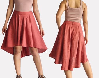 May include: A rust-colored linen skirt with pleats and a high-low hemline. The skirt is shown on a model wearing a light pink tank top and sandals. The skirt is labeled "SS03-Pleated skirt" with measurements: Waist: 28" /70cm - Hips: 38"/96cm. Model: 5'3" (1m60).