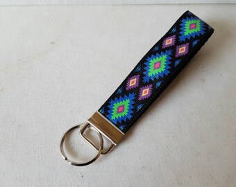 May include: A black key chain with a colorful geometric pattern. The key chain has a silver key ring.