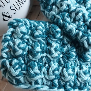 May include: A pair of teal and white crocheted pot holders. The pot holders are made with a textured stitch.