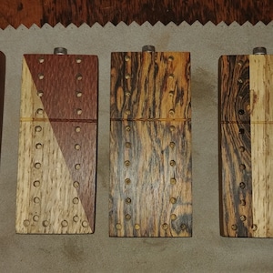 May include: Four wooden cribbage boards with different wood grain patterns. The boards are all the same size and shape, and they each have a metal hinge.