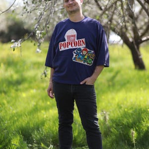 オーバーサイズのユニセックスTシャツ、ストーンウォッシュ加工のダークパープルシャツ、再利用されたヴィンテージパッチ